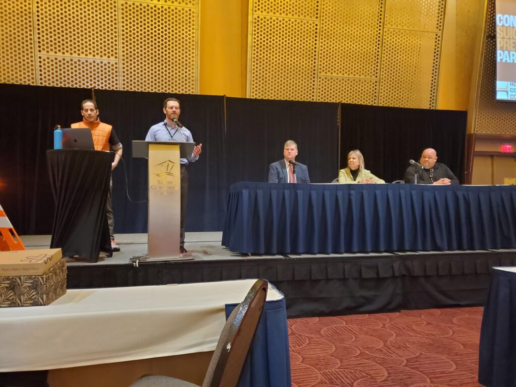 John Hickey introducing panelists Max Margolis, Dwight Holton, Lines for Life's CEO, and Sheri Sundstrom, CSPP member, at Asphalt and Pavement Association of Oregon's Paving Conference & Safety Symposium
